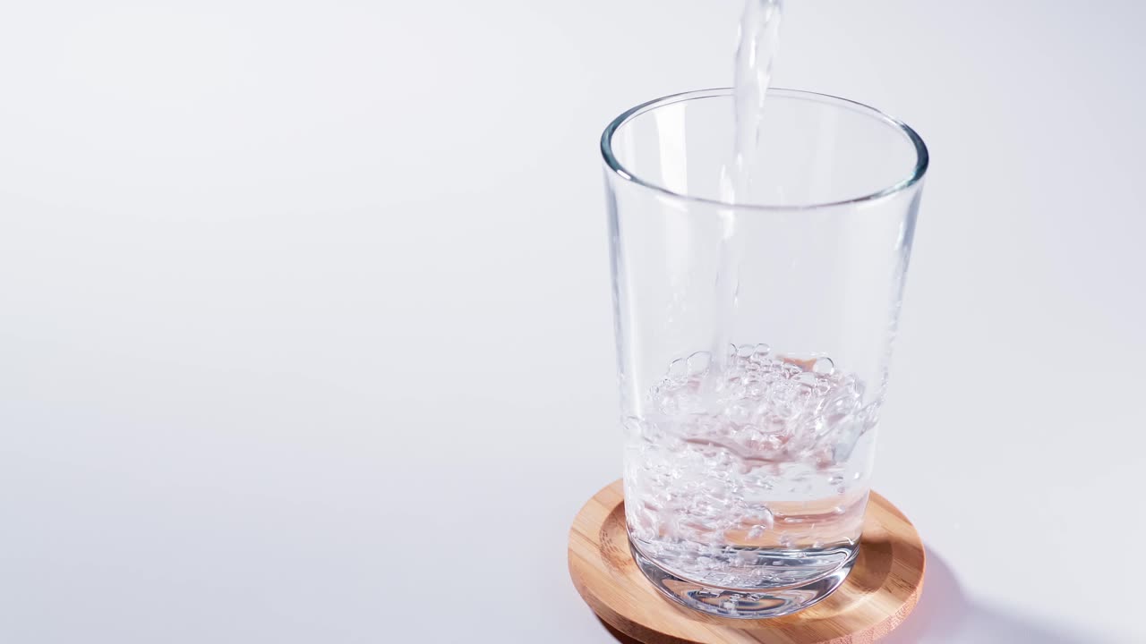 느린 동작으로 유리 근접 촬영에 순수한 물을 부었습니다.