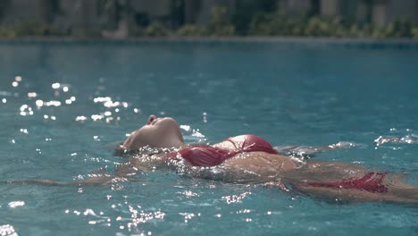 Schlanke-Dame-Im-Trendigen-Roten-Bikini-Schwimmt-Im-Kristallblauen-Pool