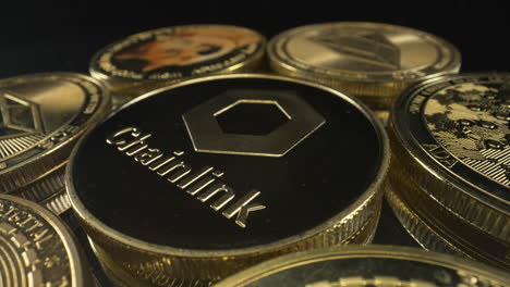 rotating chainlink coin on a pile of crypto coins turning on black background, crypto market, 4k shot