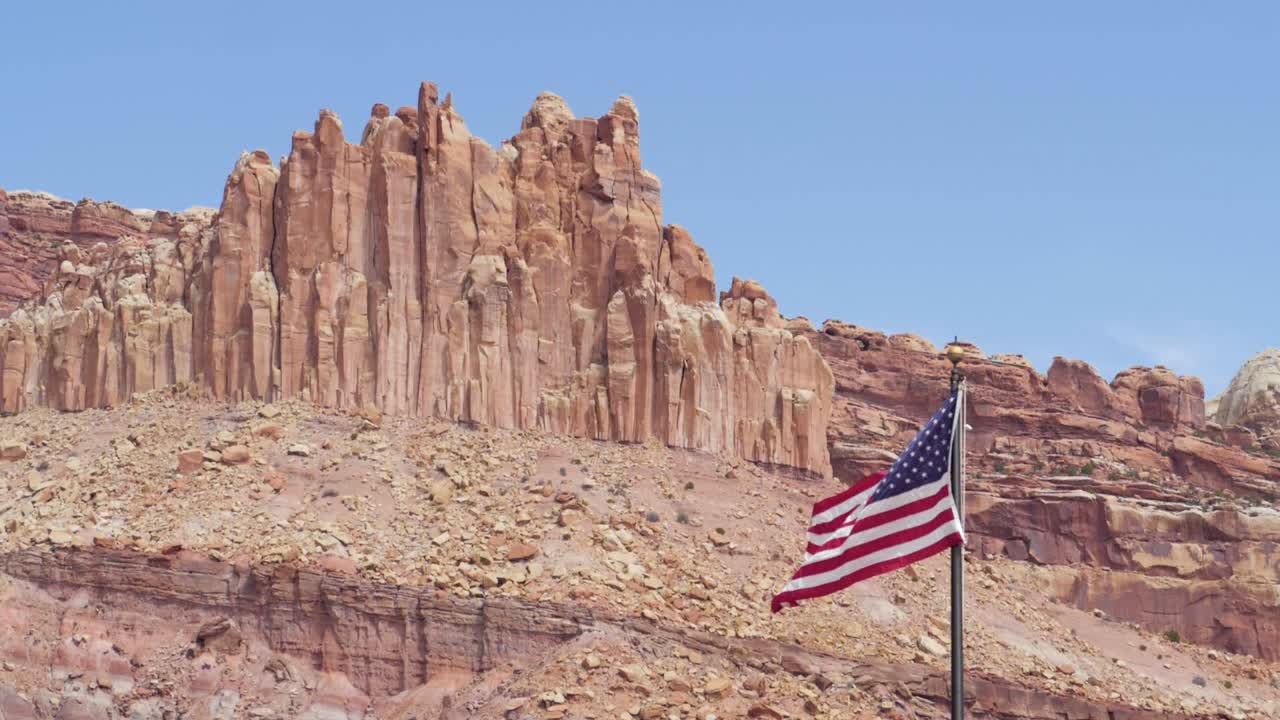 미국 유타 주 의사당 암초 국립공원의 거대한 바위 앞에서 바람에 흔들리는 미국 국기의 슬로우 모션 샷