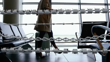 barbed wires against woman with suitcase walking in the airport