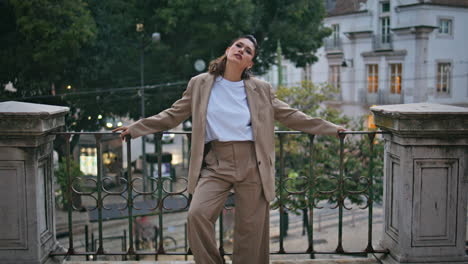 chic model standing street leaning metal railings zoom in. relaxed woman posing