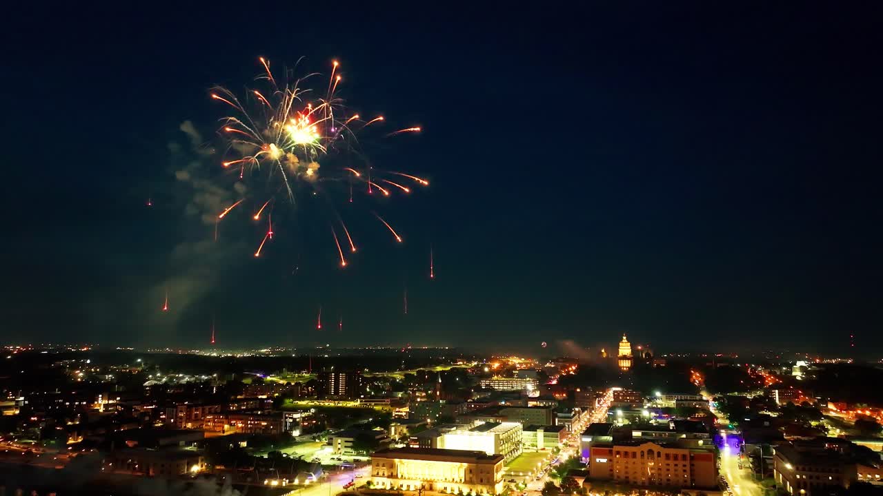 centro de des moines, iowa edificios por la noche con fuegos artificiales explotando en la celebración del día de la independencia cerca del edificio del capitolio del estado de iowa con drones video estable