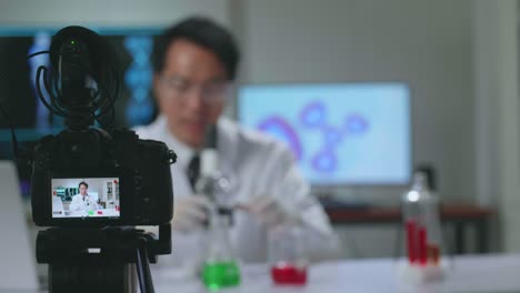camera display of asian scientist researching in the laboratory with a microscope and explain