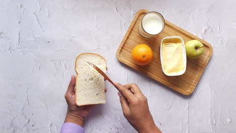 spreading butter onto toast with knife on wooden board