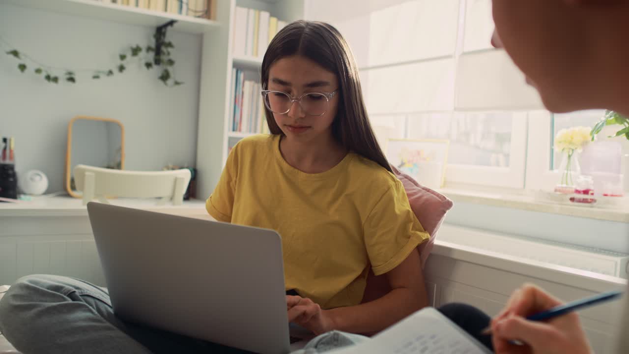 dos adolescentes caucásicos sentados en el suelo y aprendiendo de libros y portátiles