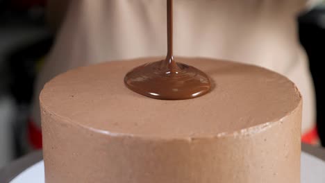 pastry chef pours liquid chocolate on the top of the cake to decorate it.