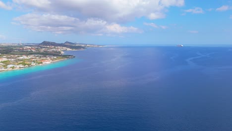 Cruise-ship-on-horizon-with-current-plumes-off-coast-of-Willemstad-Curacao,-aerial