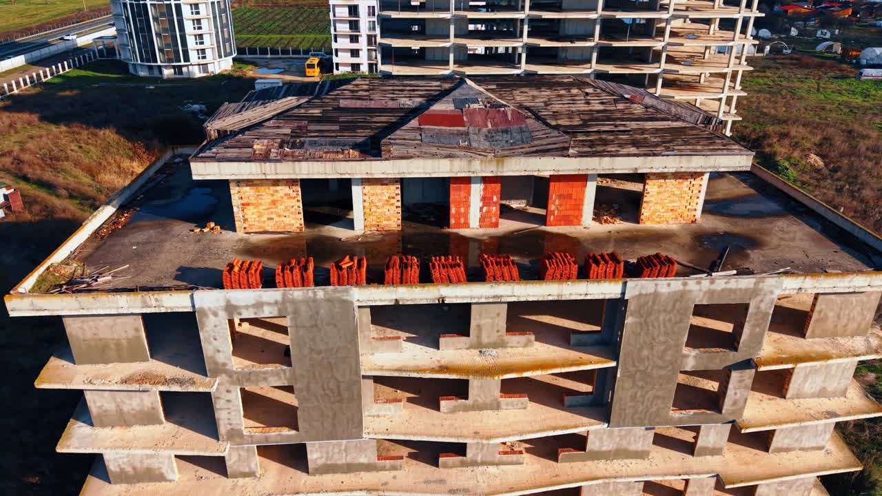 Vuelo alrededor de la cima del edificio en construcción. Pilas de tejas rojas almacenadas en el tejado