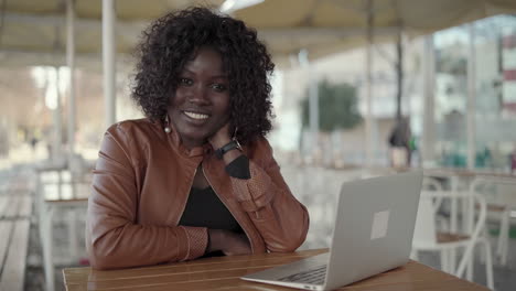 happy african american woman working with laptop in cafe