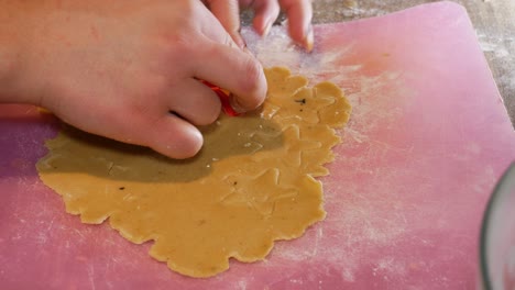 Close-up-side-view-of-a-female-hand-making-a-gingerbread-cookie-in-the-form-of-a-star