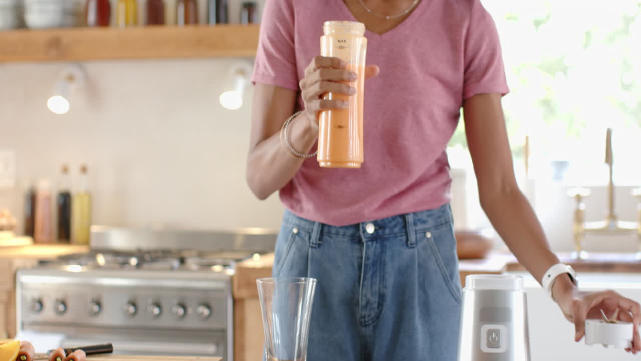 Pouring fresh juice into glass, woman in modern kitchen, excited, at home