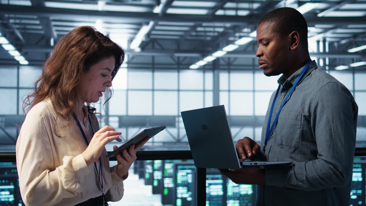 Team of technicians working in server farm, using laptops to analyze data
