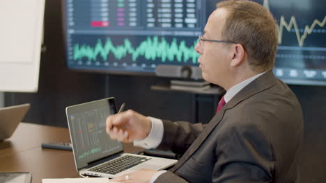 Man-Sitting-In-Monitoring-Room-And-Talking-With-Colleague