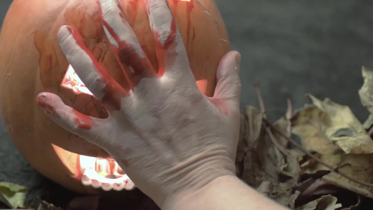 Bloody hand slides down carved pumpkins Jack o lantern Halloween