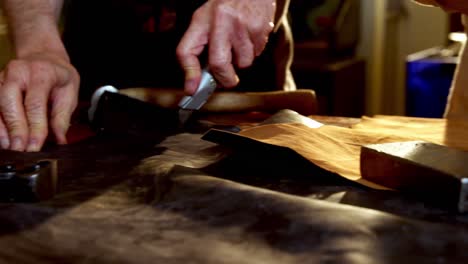 shoemakers cutting a piece of leather