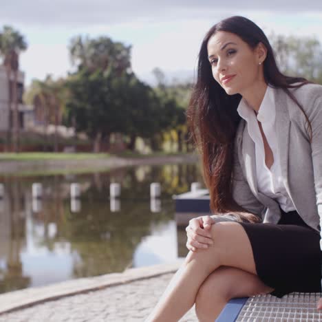 Business-woman-sitting-on-bench-looking-away