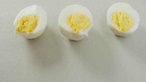 Video-of-close-up-of-three-halves-of-hard-boiled-eggs-on-grey-background