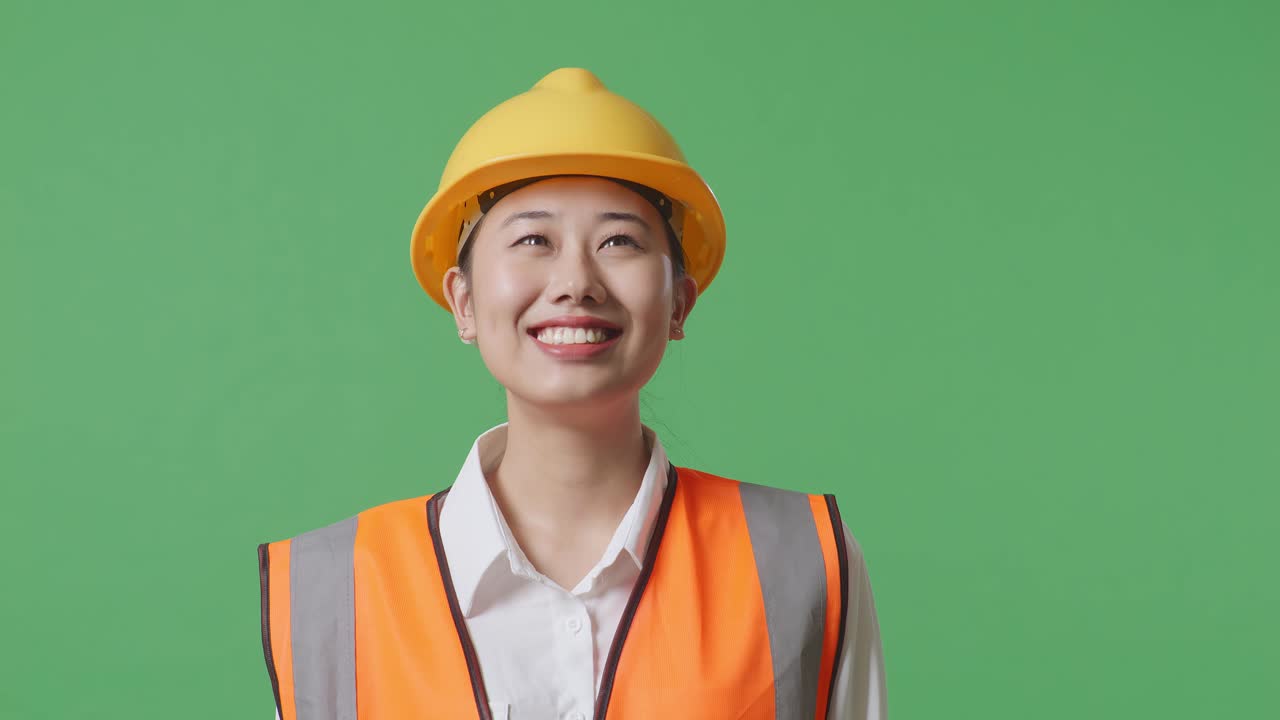 Close Up Of Asian Female Engineer With Safety Helmet Looking Around While Standing In The Green Screen Background Studio