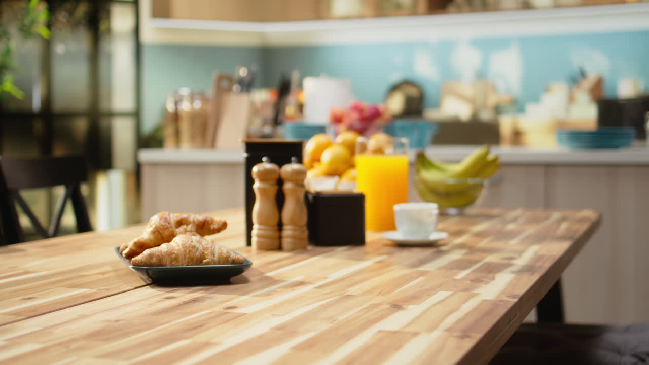 Empty breakfast table in a modern kitchen featuring croissants on plate