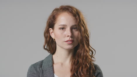 Head-And-Shoulders-Studio-Portrait-Of-Serious-Young-Businesswoman-Against-Plain-Background