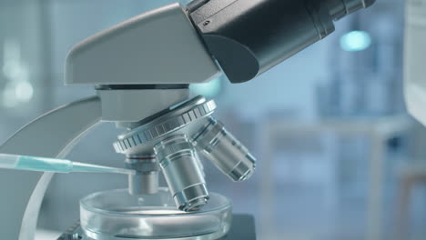 científico negro con ropa de protección examinando productos químicos a través del microscopio