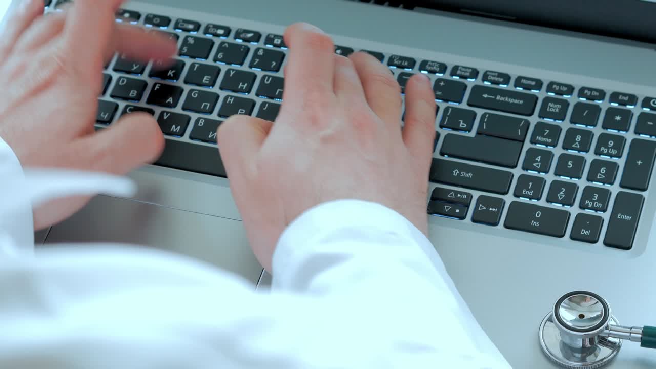 A fanendoscope, laptop, hands of a doctor’s doctor print on a keyboard, a view of the top, a selective focus