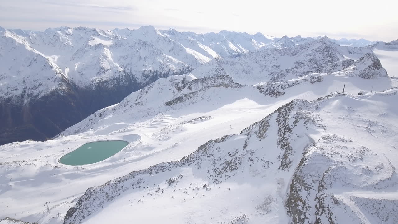Drone che si inclina verso il basso su un bellissimo lago di montagna e un punto panoramico, rivelando una pista da sci, a Sölden, Austria. 4K