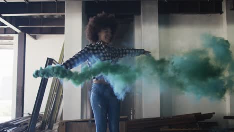 Mixed-race-woman-holding-green-flare-dancing-in-an-empty-building