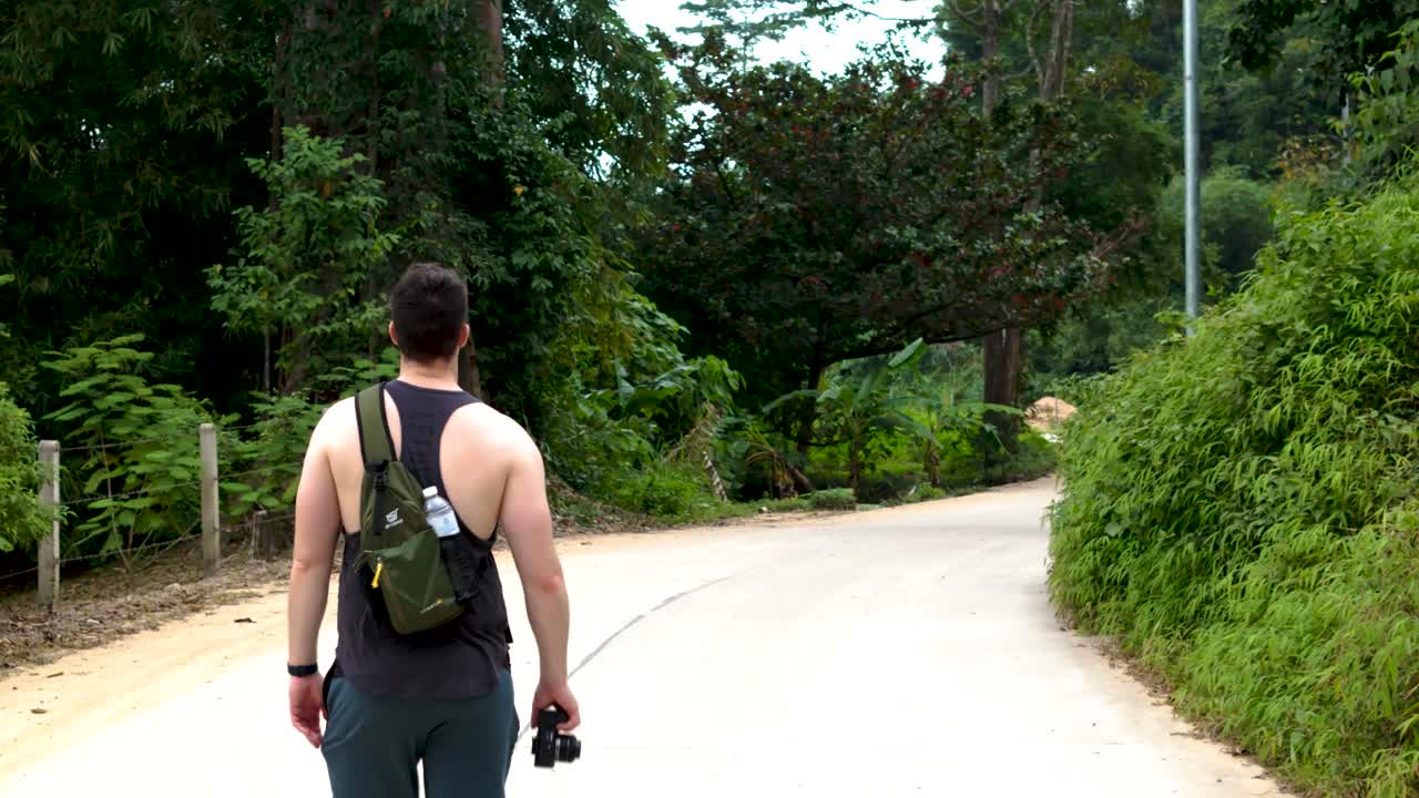 Caucasian man on holiday walking around with a camera, tropical street on the Island of Koh samui, Thailand.