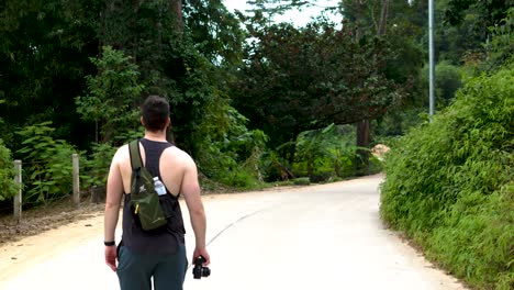 caucasian man on holiday walking around with a camera, tropical street on the island of koh samui, thailand.