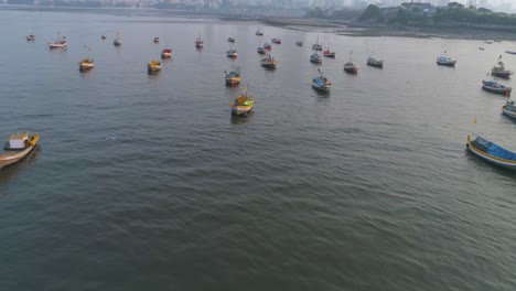 volando sobre los barcos de pescadores estacionados en el koliwada junto al fuerte worli, revelando la vista del paisaje urbano de mumbai con rascacielos en la parte trasera con asentamientos para contrastar