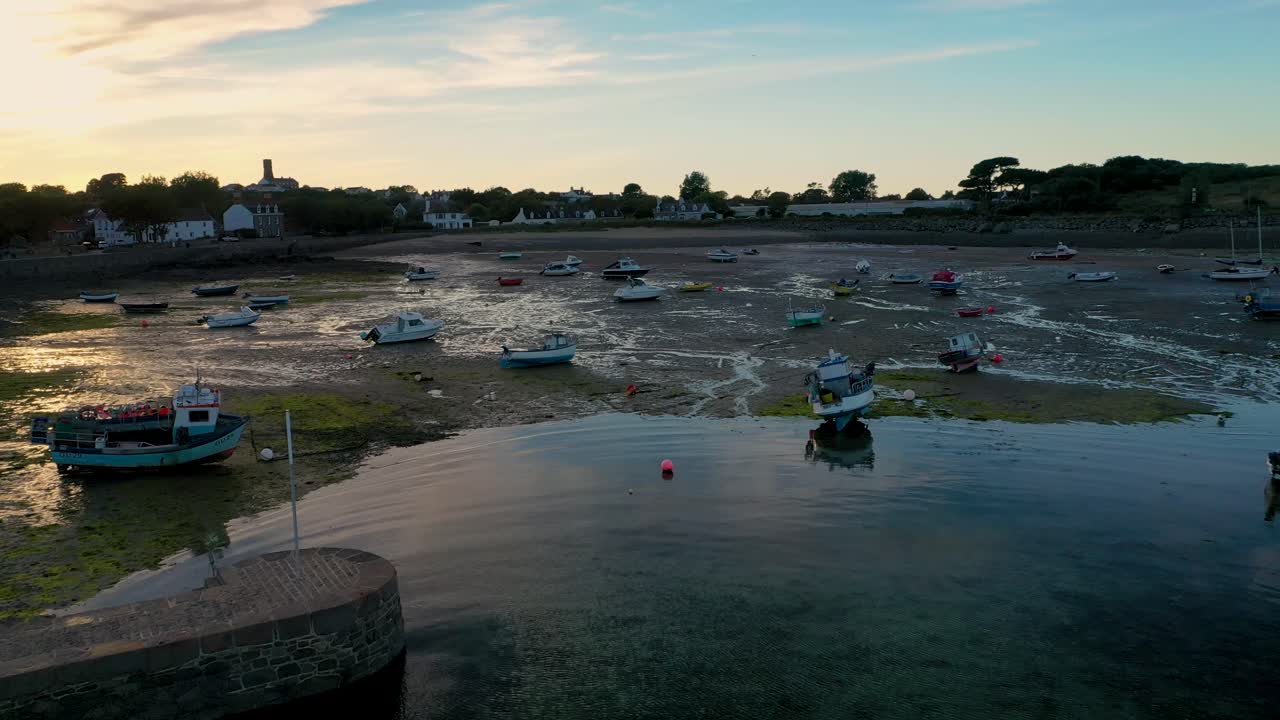 vuelo hacia adelante sobre el puerto de burdeos guernsey a marea baja con pared del puerto, barcos secos y sol de verano temprano en la noche