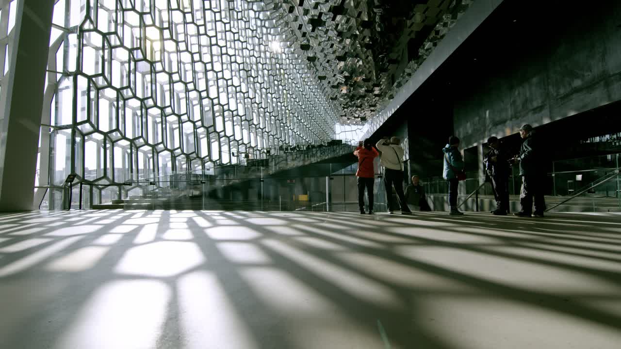 Tourists admire the modern architecture inside Reykjavik Opera House in Iceland during the day