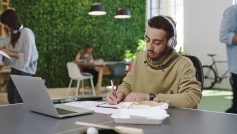 Headphones,-laptop-and-businessman-in-busy-office