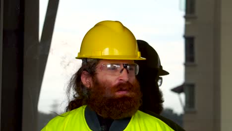 portrait of a construction worker smoking in extreme slow motion outdoors on break at job site in urban city setting with sky reflection as background