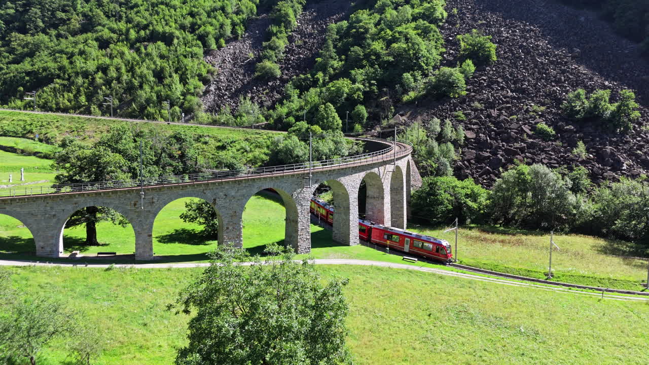 Scenic train on stone viaduct in lush green valley during sunny summer day