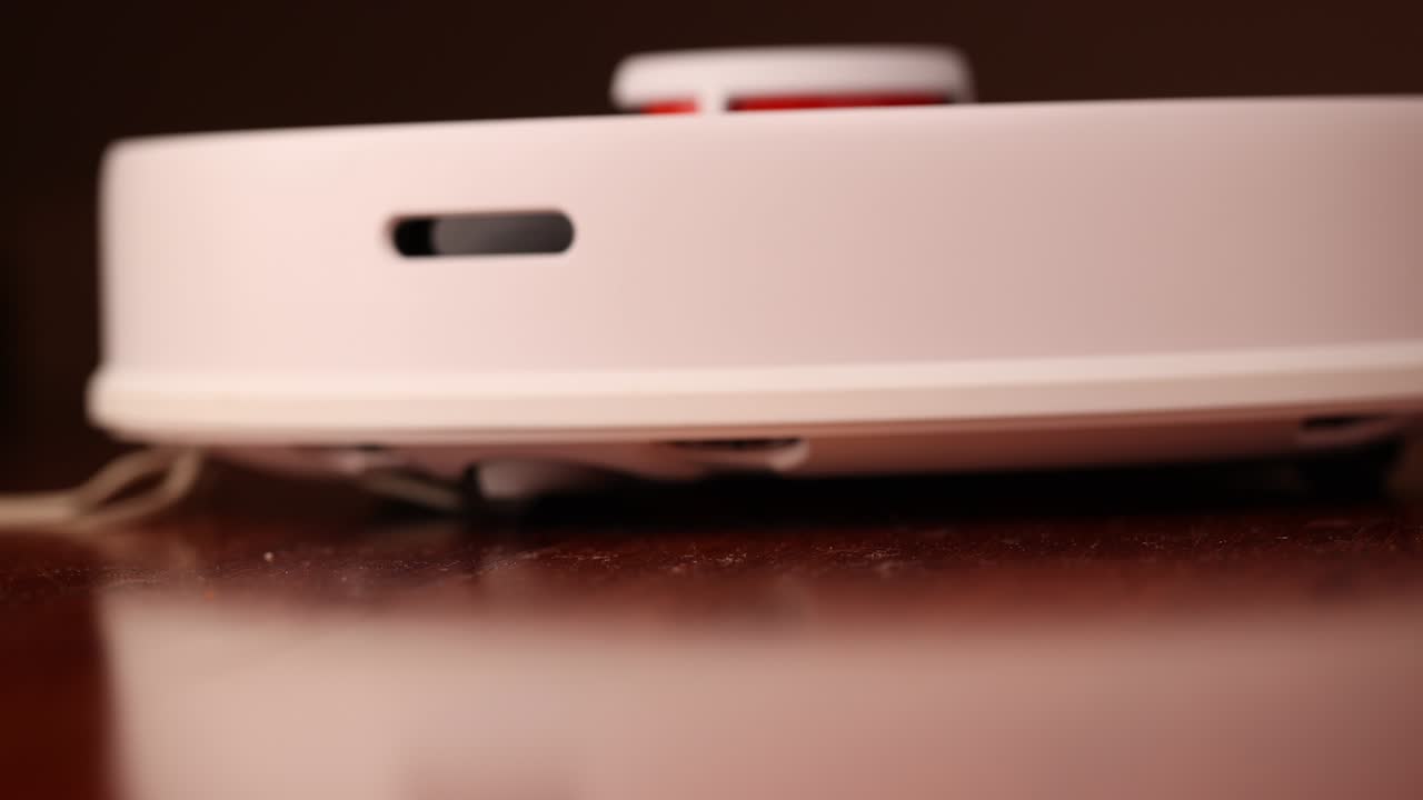 나무 바닥에 리더를 가진 스마트 로 진공청소기 로 진소기는 아파트의 자동 청소를 수행합니다. 느린 동작 100fps.