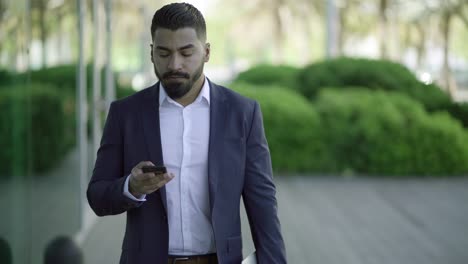 Serious-bearded-man-with-laptop-and-mobile-phone-outdoor