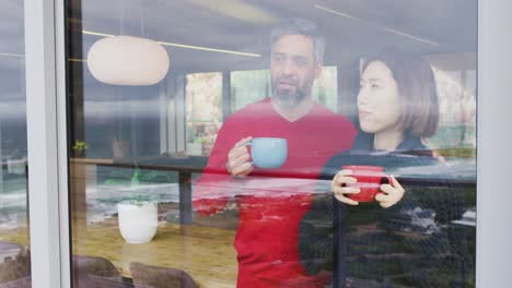 una pareja feliz y diversa bebiendo café y hablando juntos en casa
