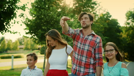 niños y padres caminando en el parque de verano. padre sosteniendo la mano de la hija