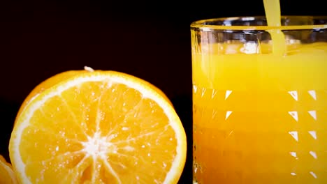 a detailed view of a glass filled with orange juice beside a fresh orange slice.
