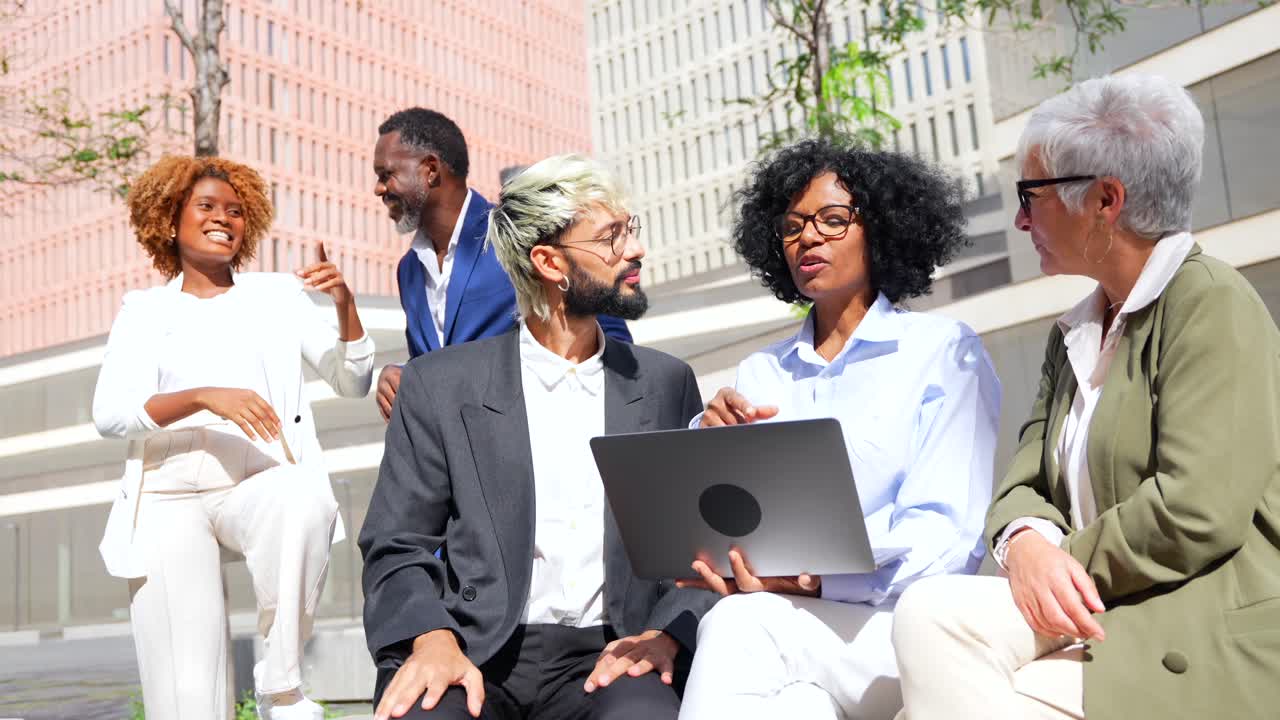 Équipe d’affaires diversifiée collaborant à l’extérieur avec un ordinateur portable