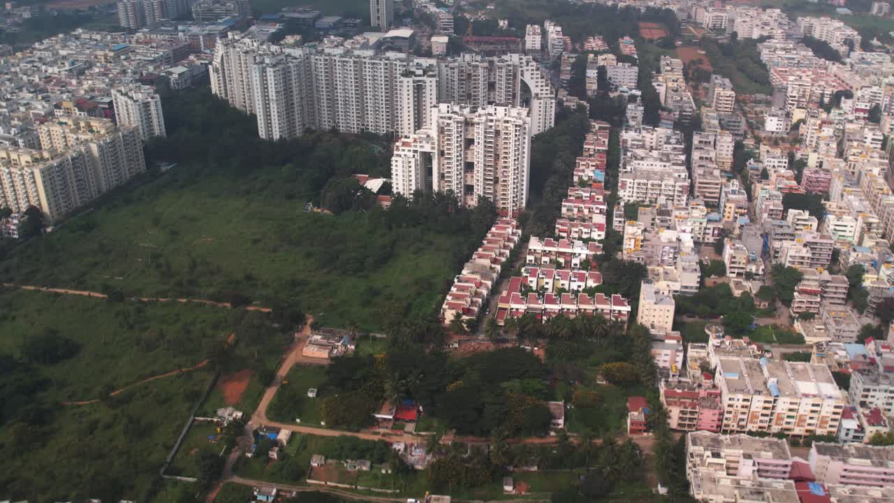 An aerial view overlooking a residential neighborhood and business buildings displays an empty, greenish area