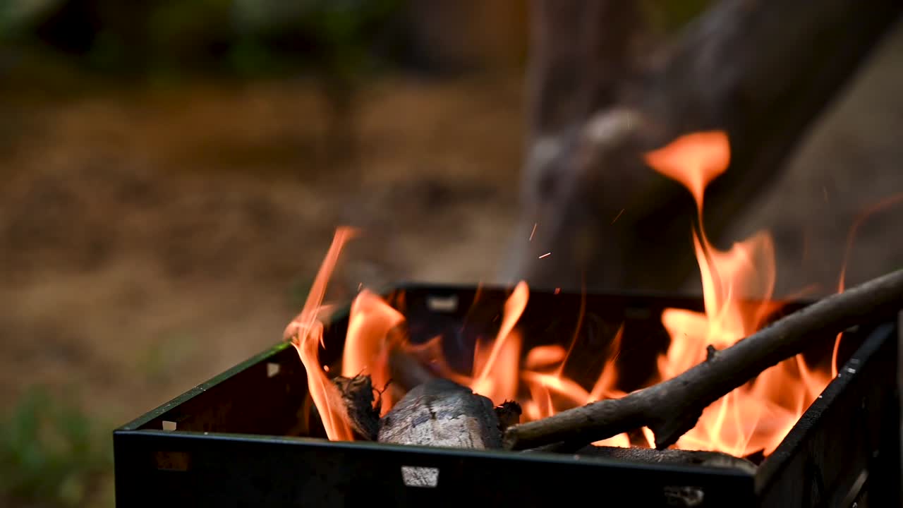 Slow-motion footage of wood burning in a barbecue grill, flames rising to create perfect heat for outdoor cooking. Great for food, barbecue, camping, lifestyle, and sustainable cooking themes