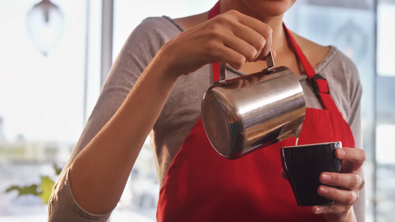 커피 를 준비 하는 동안 커피 컵 에 우유 를 부는 웨이트리스