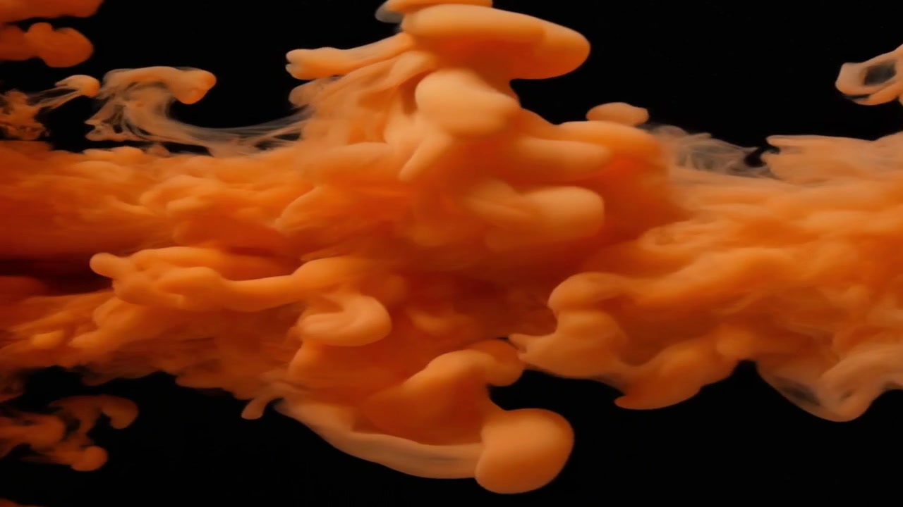 Orange blæk hvirvler i vand på sort baggrund