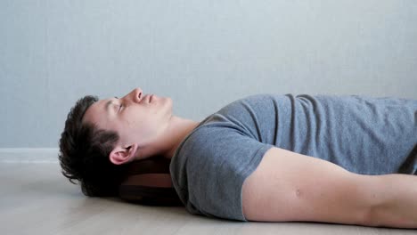 tired guy is lying on the floor with electric massage pillow.