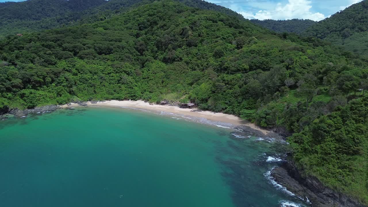 Aerial drone view of secluded tropical beach on Koh Lanta with lush green hills and dense forest, calm turquoise water, untouched coastline and peaceful natural scenery, captured with no people