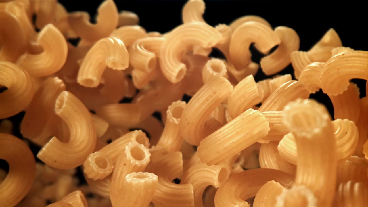 Pasta di maccheroni a gomito secchi che cadono al rallentatore